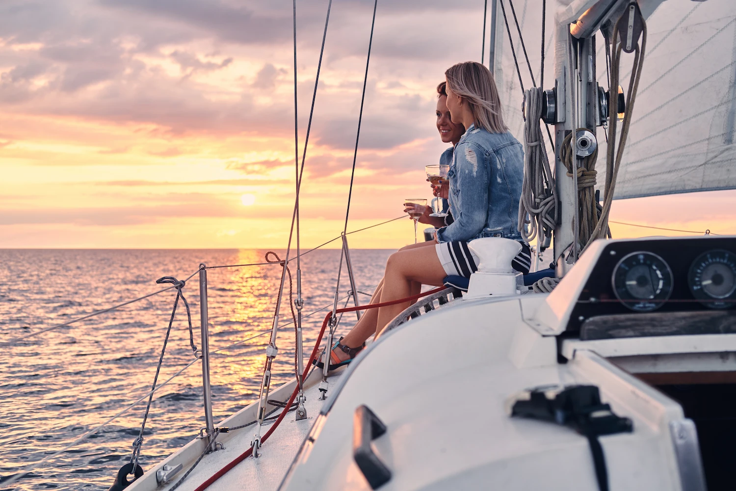 a couple sitting on a sail boat looking out over the ocean